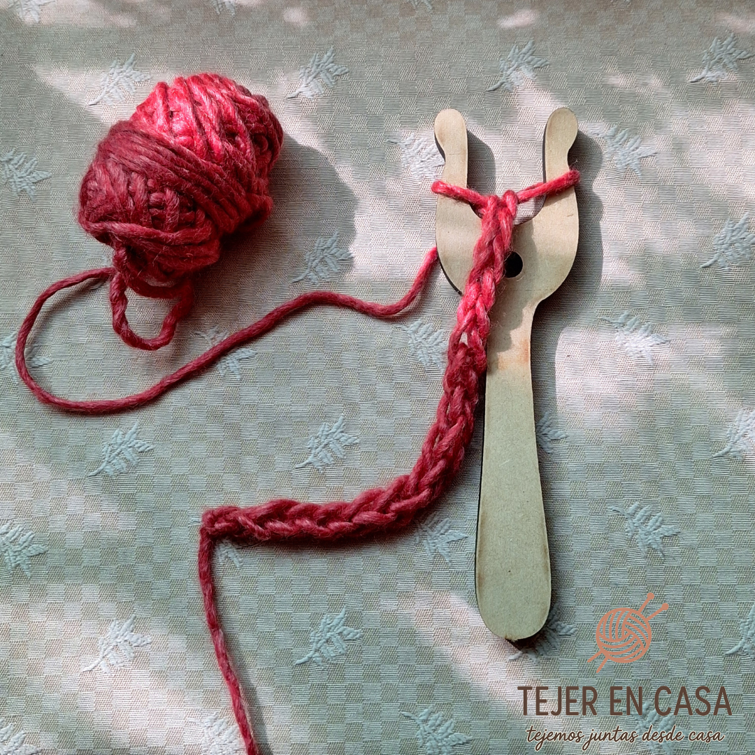 Luceta de madera con hilo rojo usada en técnicas de tejido antiguas